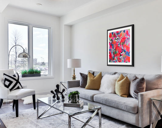 Modern living room with a gray sofa, coffee table, and colorful abstract art on the wall.
